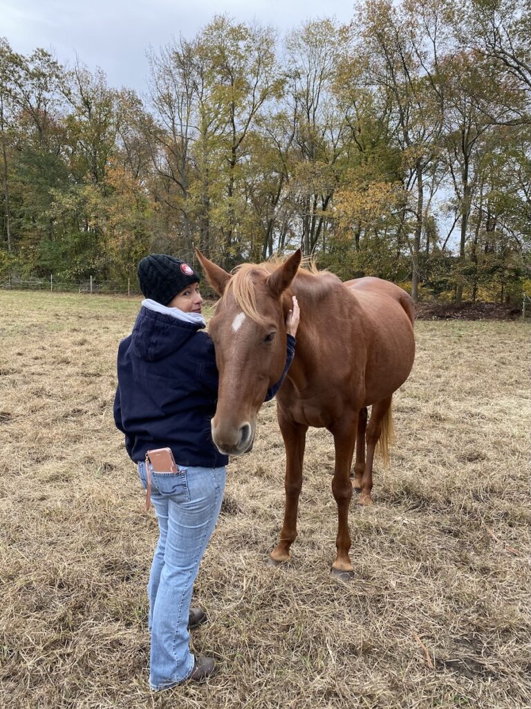 a woman standing next to a horse